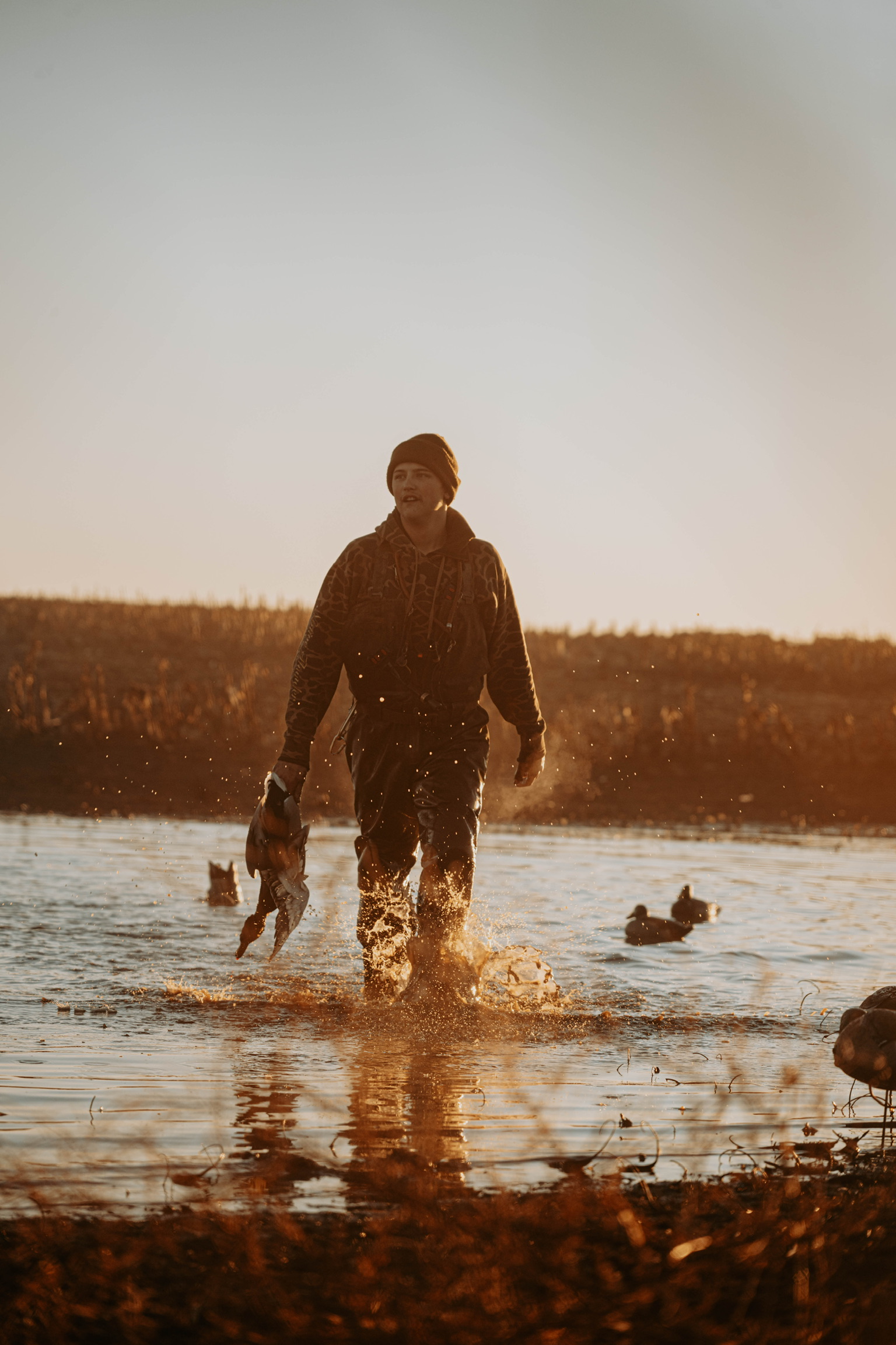 A lone hunter wading out at sunset